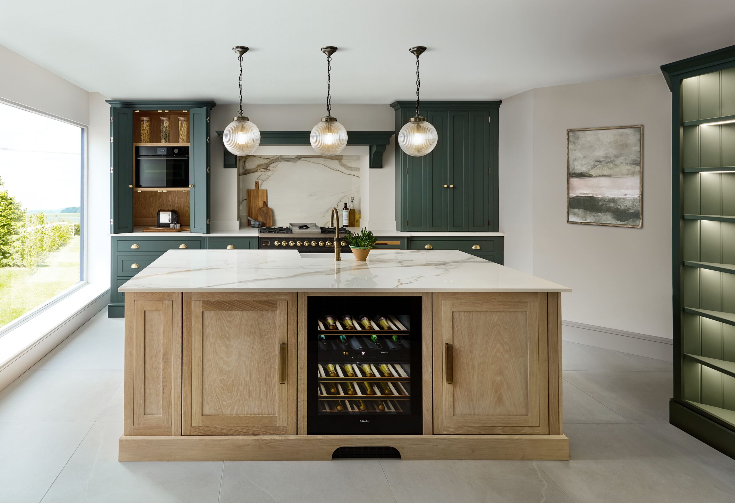 Modern shaker kitchen with dark green outer cabinetry and solid wood island with wine fridge and pendant lighting